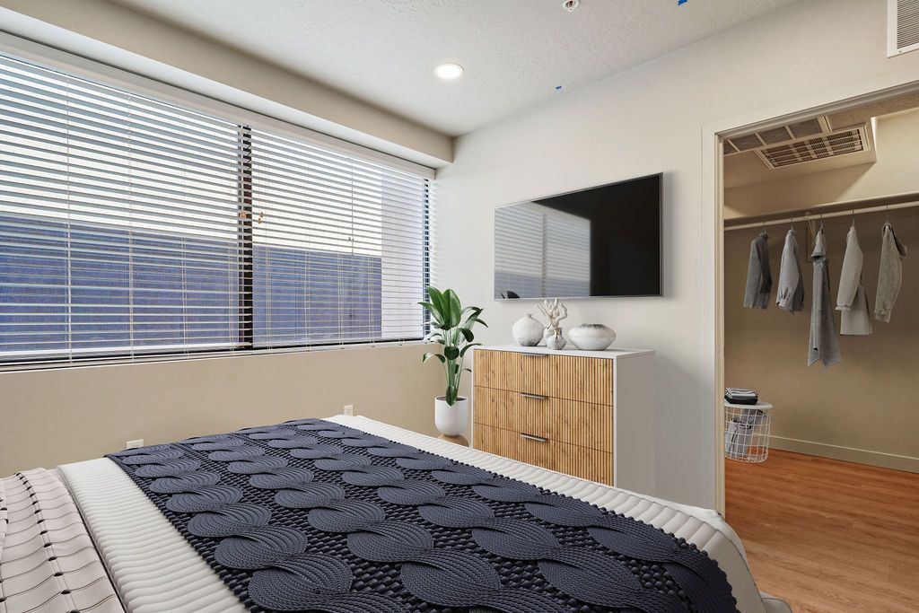 A bedroom with a bed , dresser , television and walk in closet.