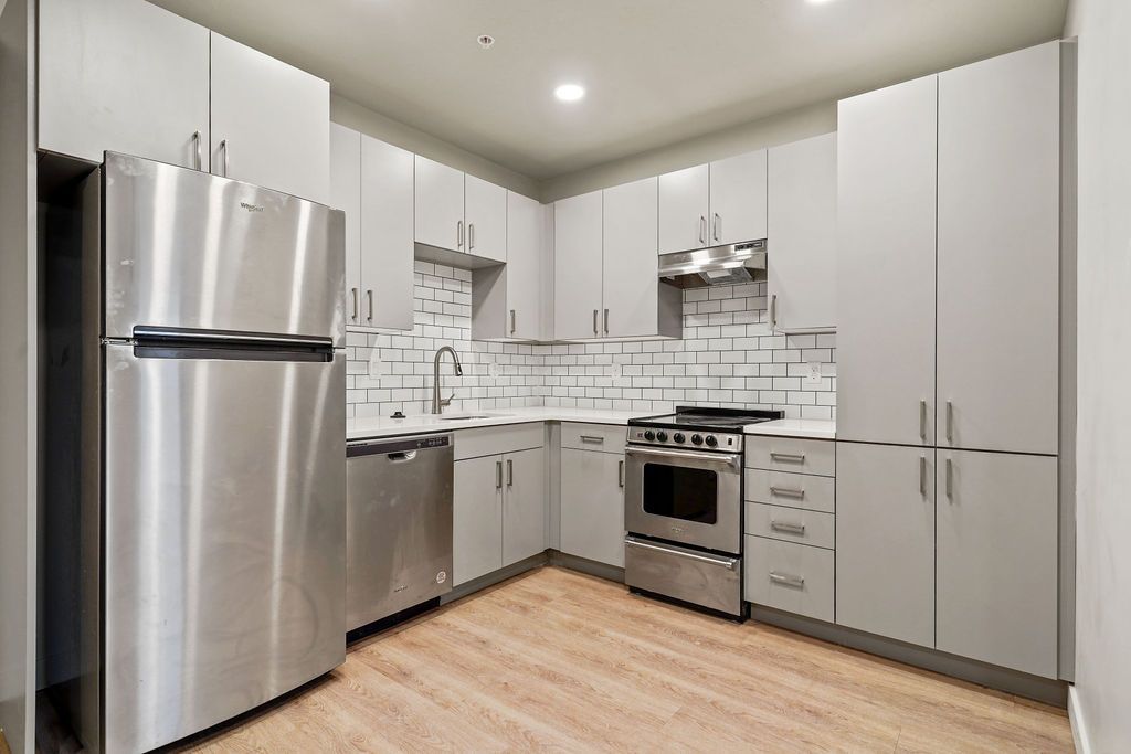 A kitchen with stainless steel appliances and white cabinets.