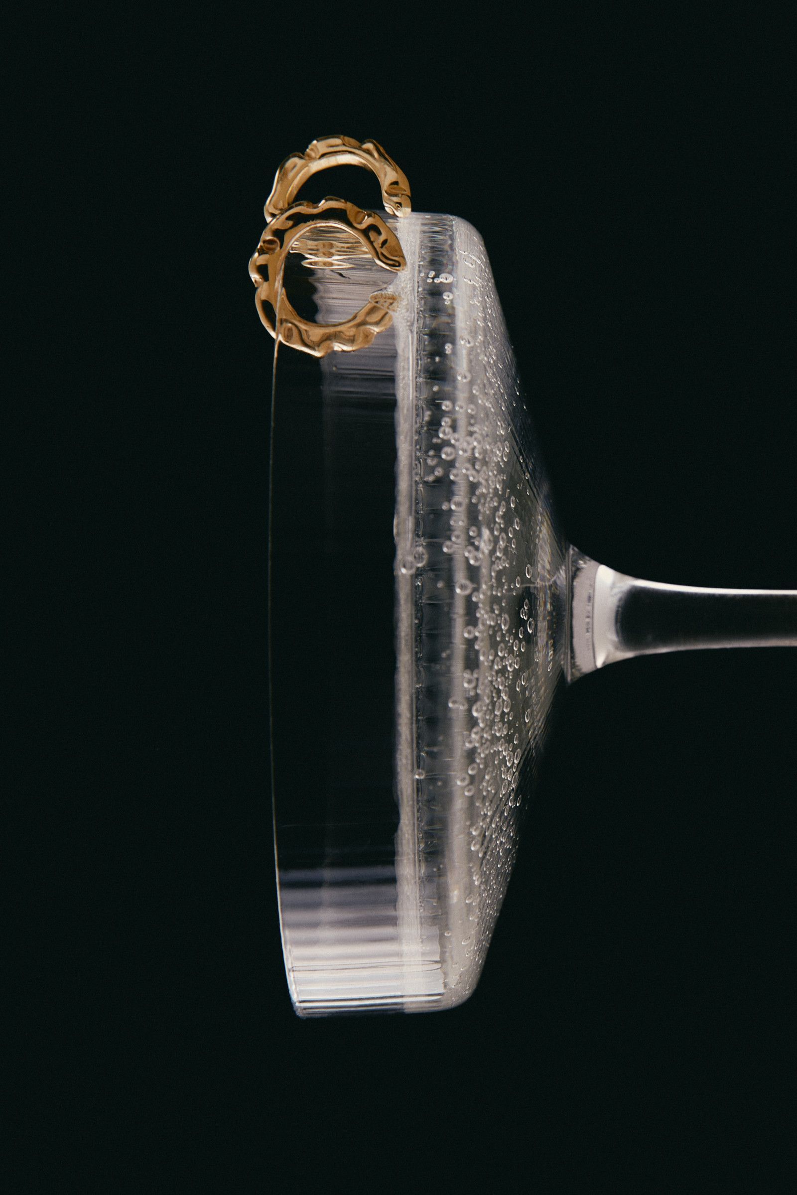 Close-up of a wine glass rim with frothy liquid spilling over the edge against a dark background