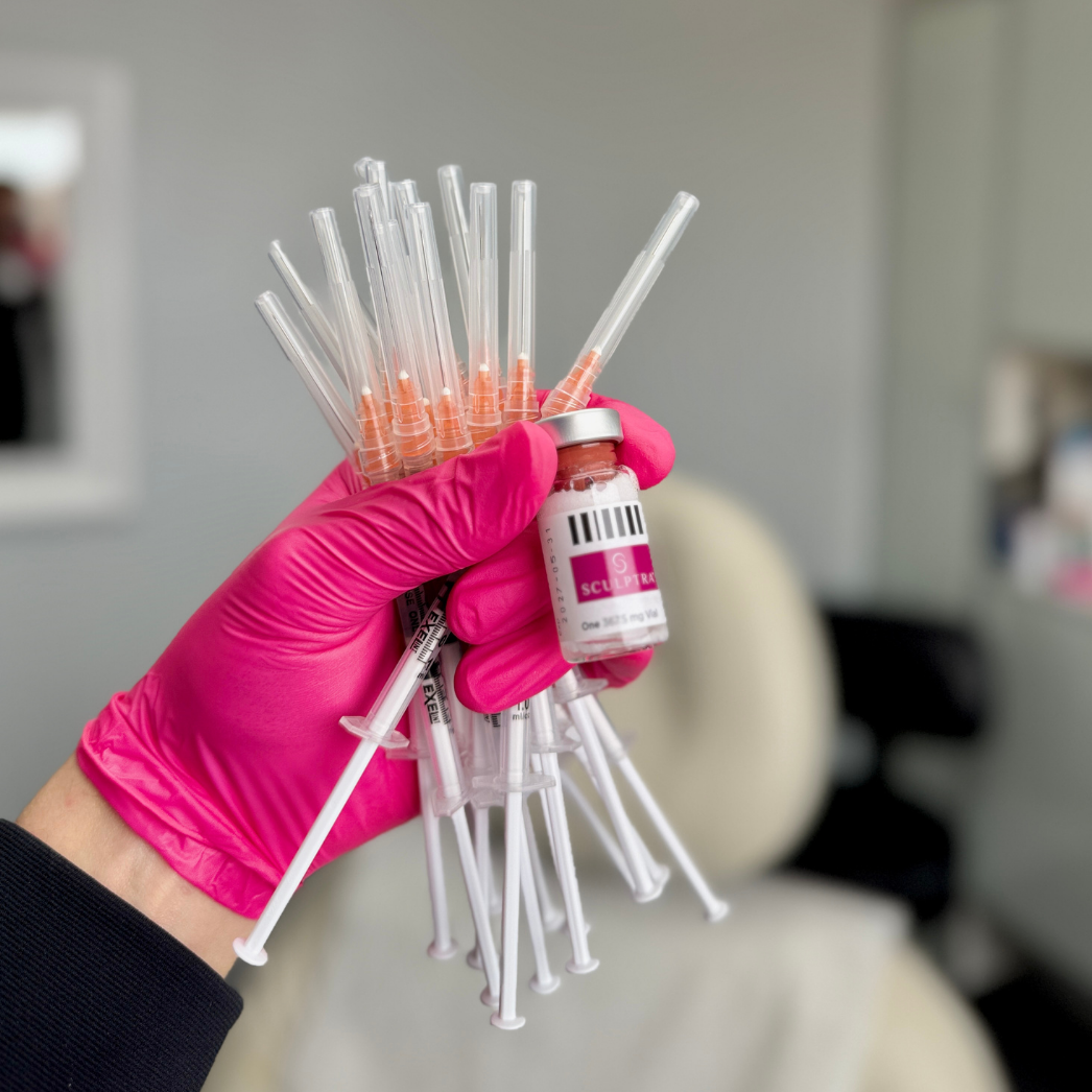 Gloved hand holding a bundle of syringes and a vaccine vial in a clinical setting