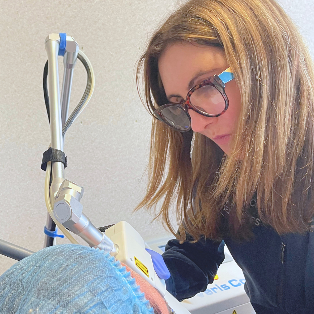 Woman using a handheld device on a patient’s leg in a clinical setting