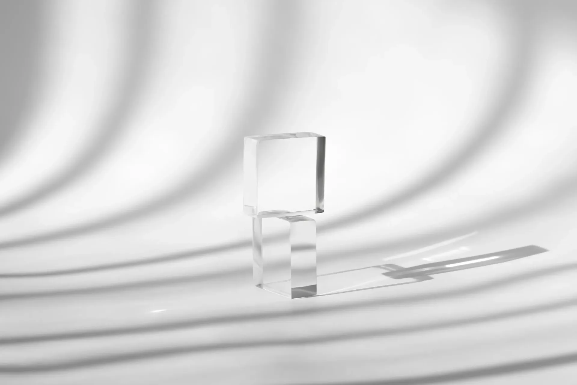 Clear glass on rippled white surface with soft shadows