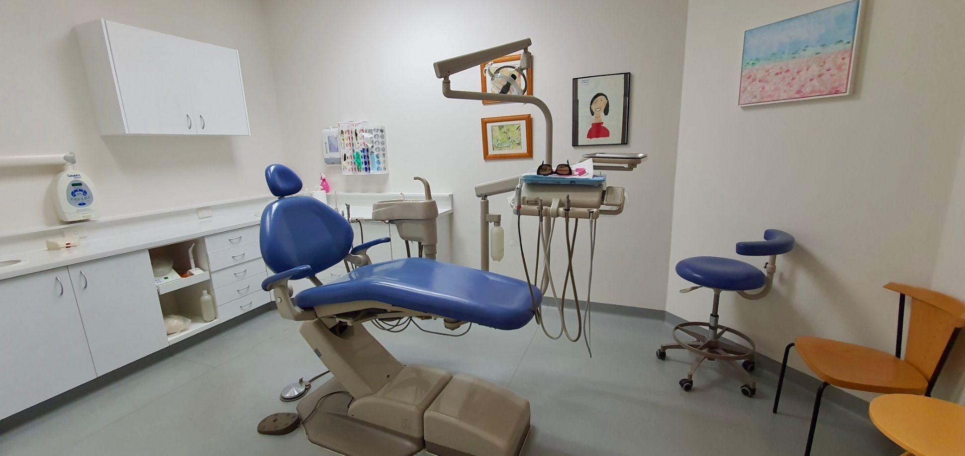 A dental office with a blue dental chair and chairs.