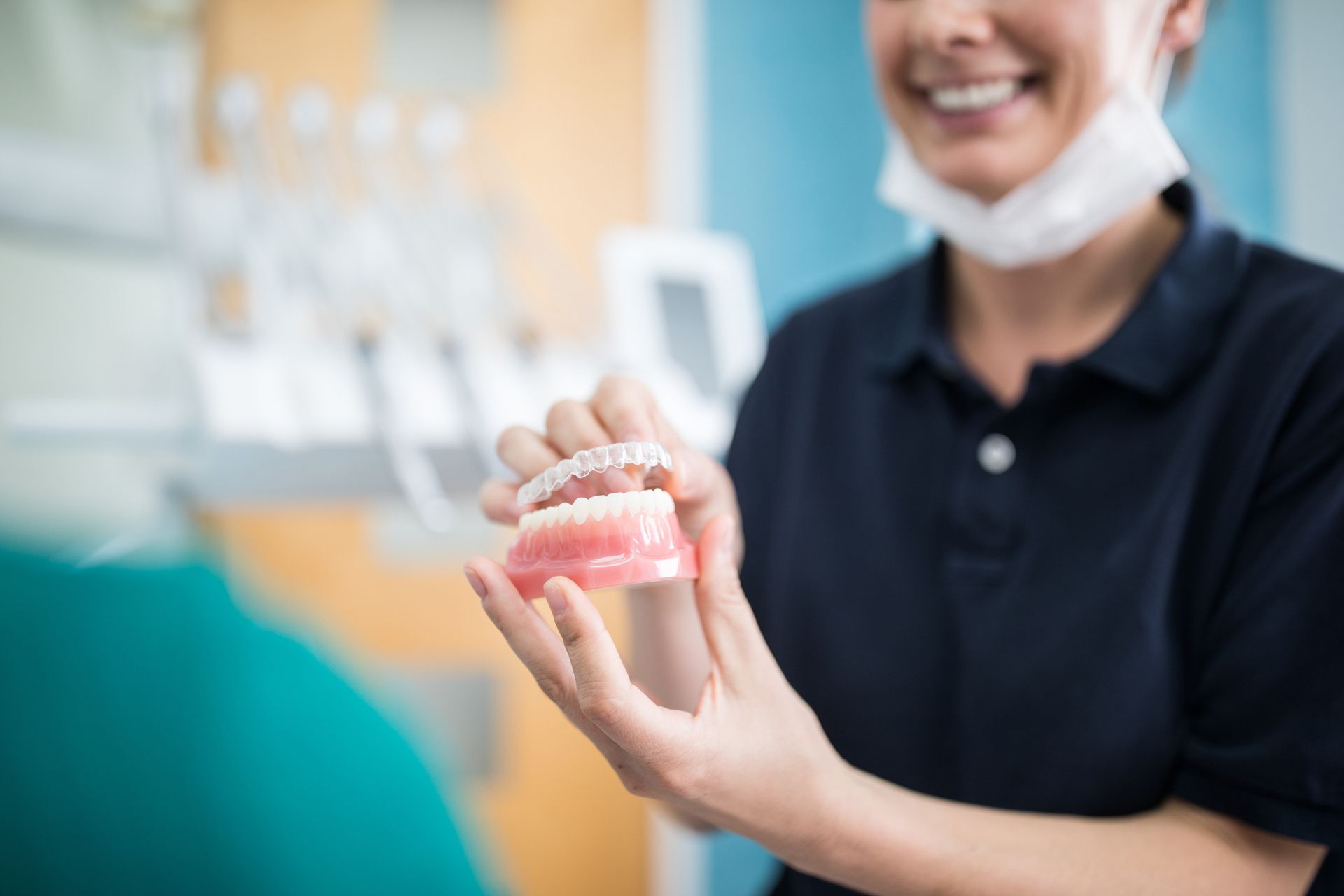 A dentist is holding a model of teeth in her hands.