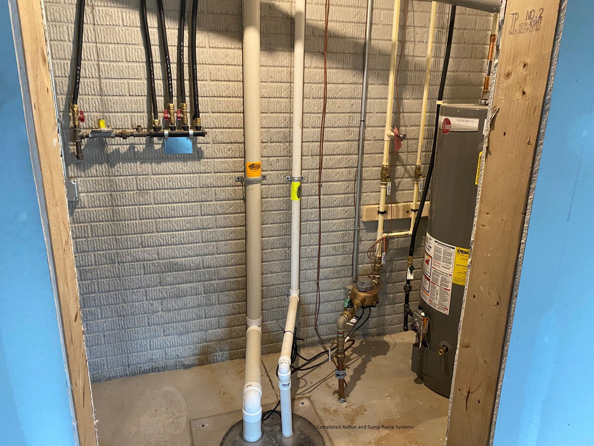 a basement with a brick wall , pipes , and a furnace .