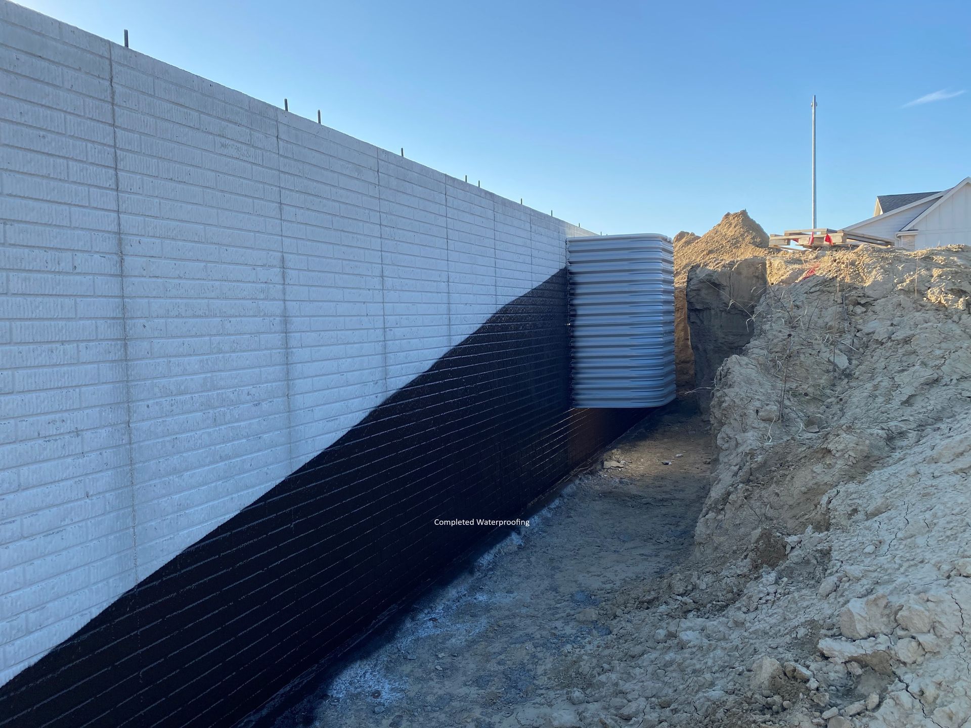 a white brick wall is being built next to a pile of dirt .