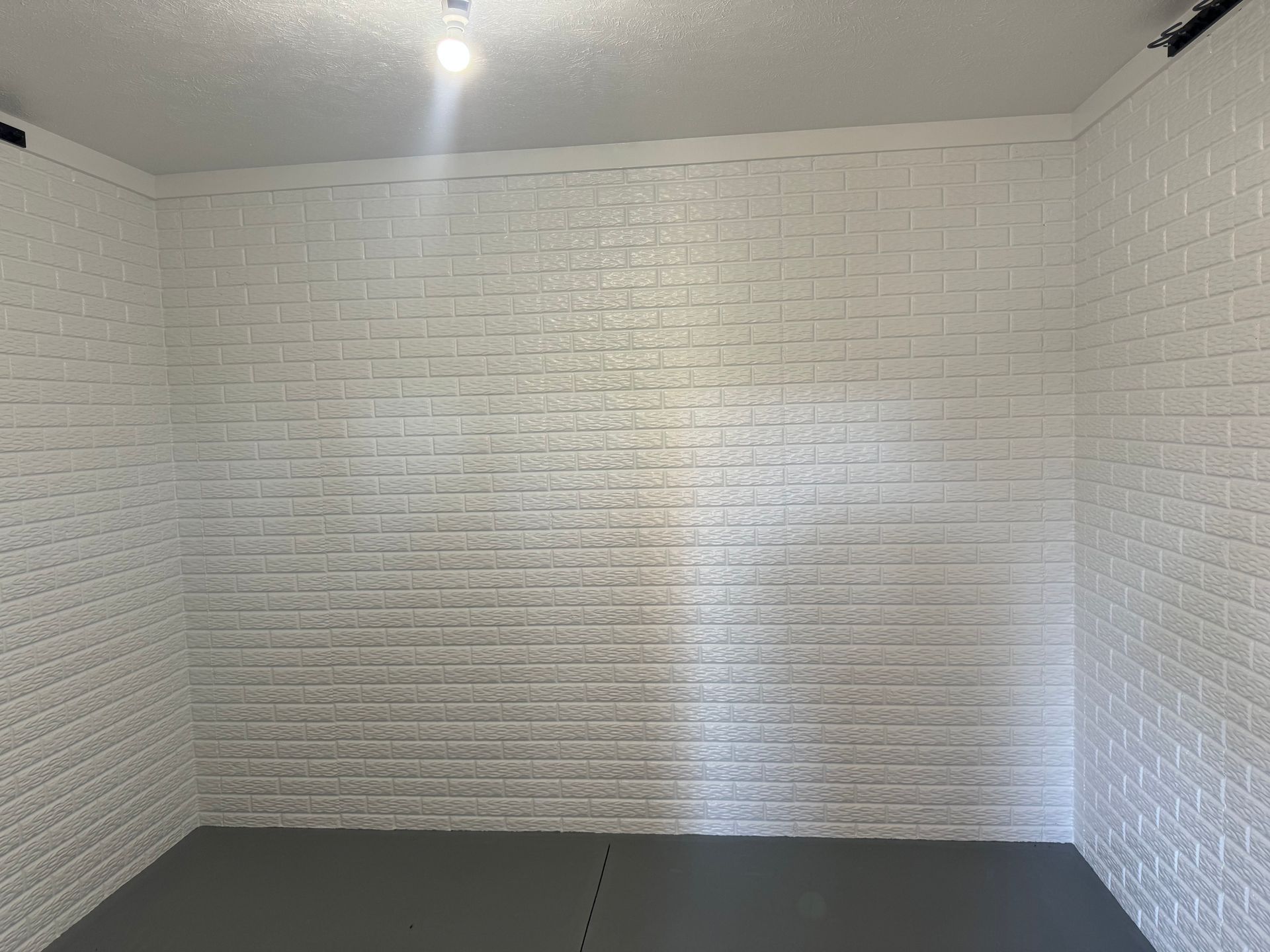 a room with white brick walls and a gray floor .