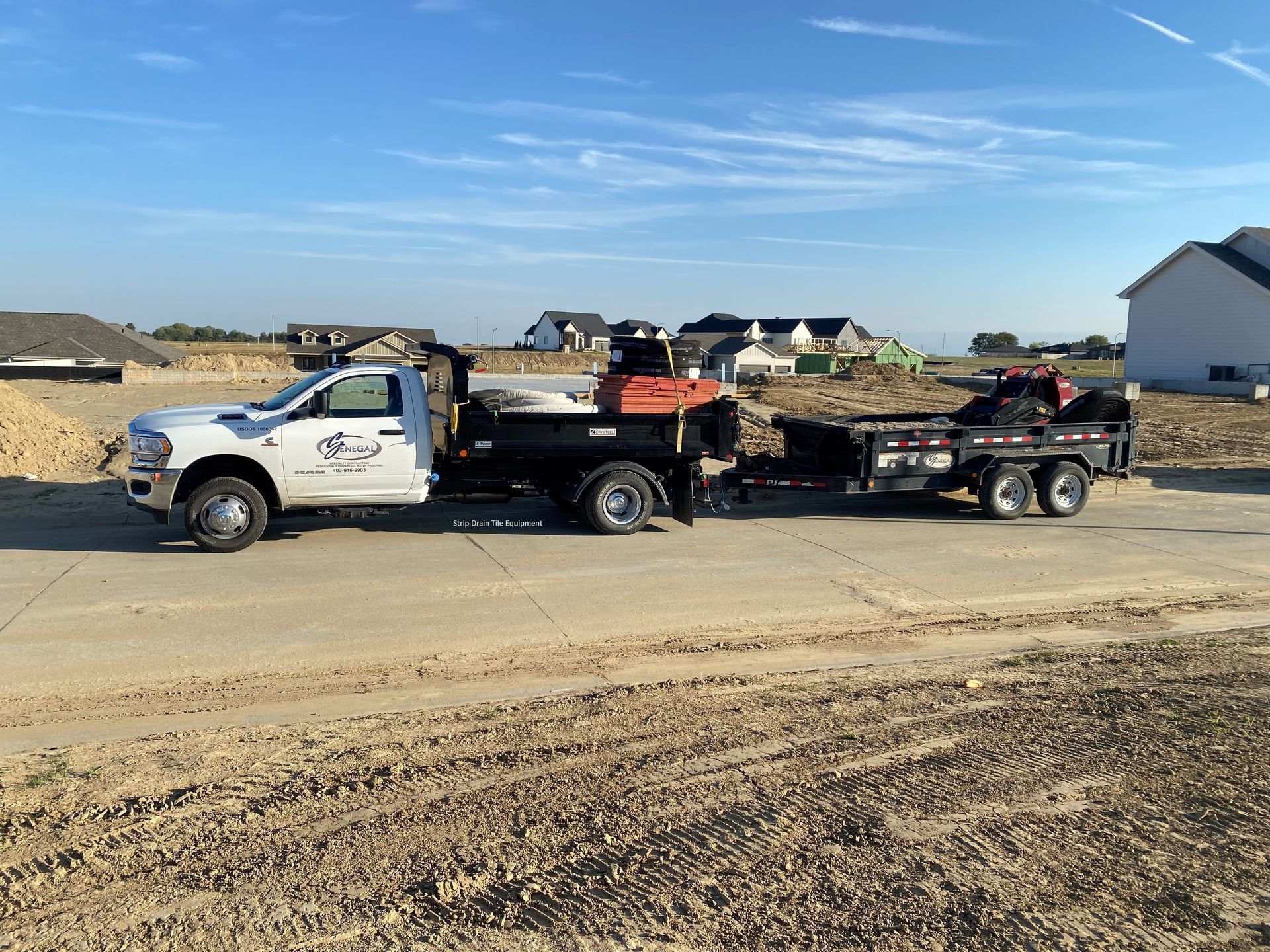a white truck with a trailer attached to it is parked on the side of the road .