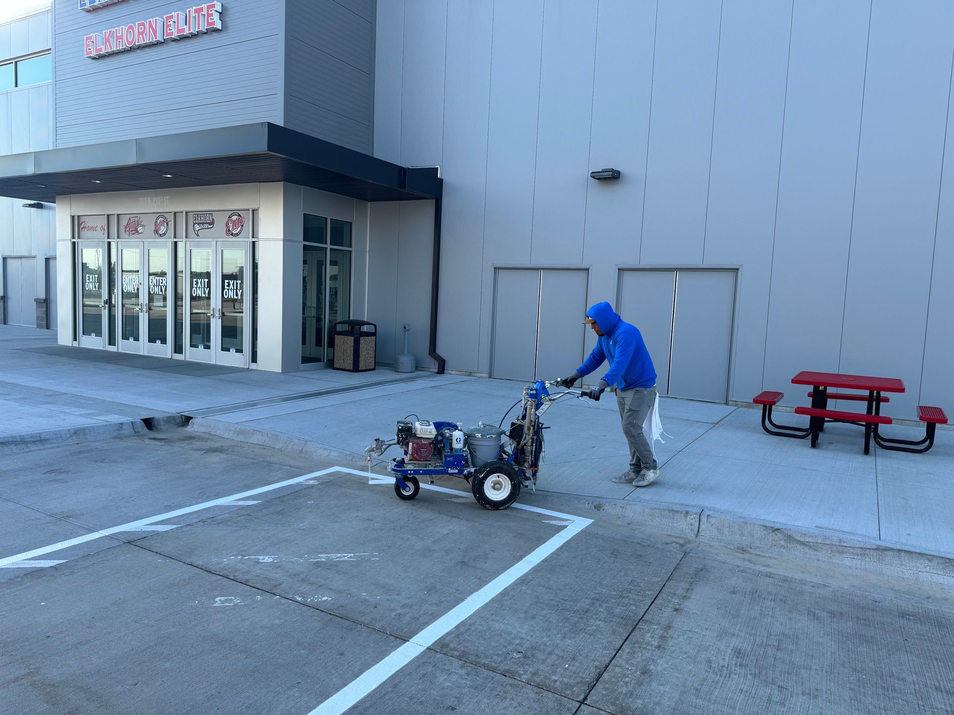 a man is using a machine to paint a line in a parking lot .
