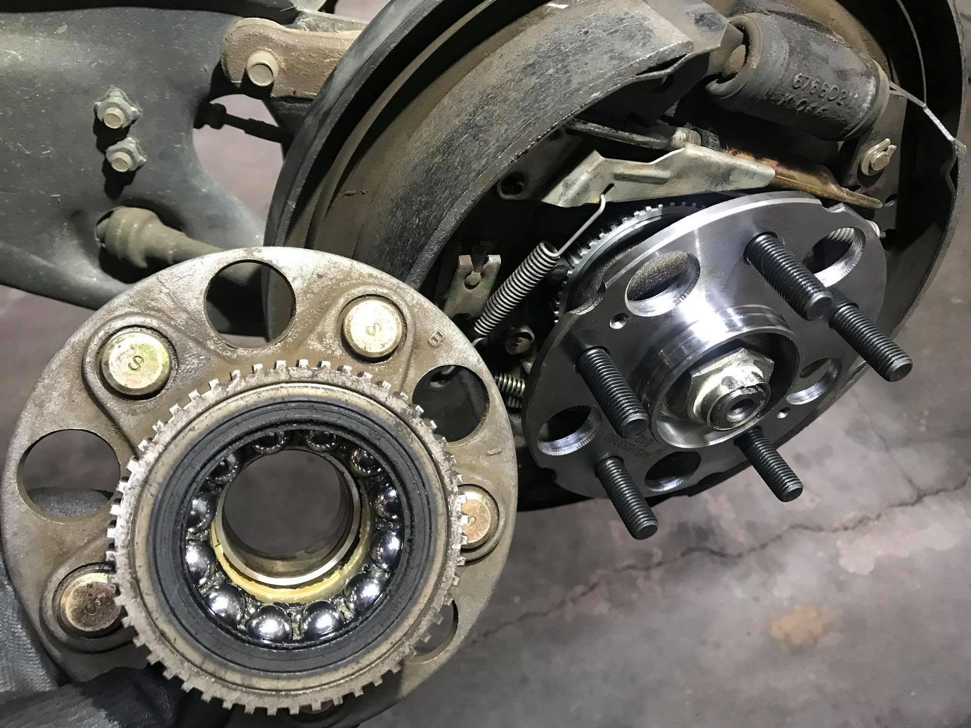 Close-up of a car wheel hub and brake assembly with exposed bearings and studs on a workbench. | Lakeside Automotive