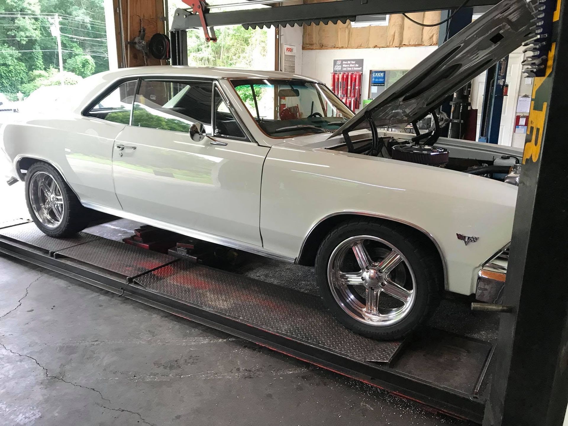 White classic muscle car on a shop lift with hood open in a garage | Lakeside Automotive