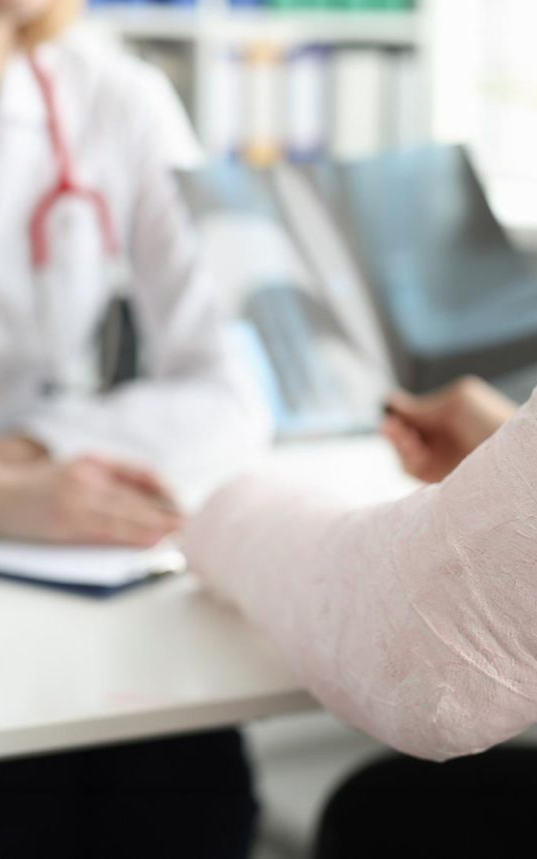 Doctor showing X-ray to patient with arm in a cast at a doctor's office.