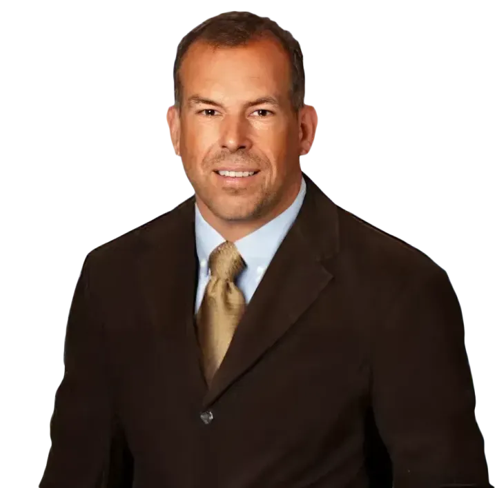 Studio portrait of a man in a dark suit and gold tie on a white background