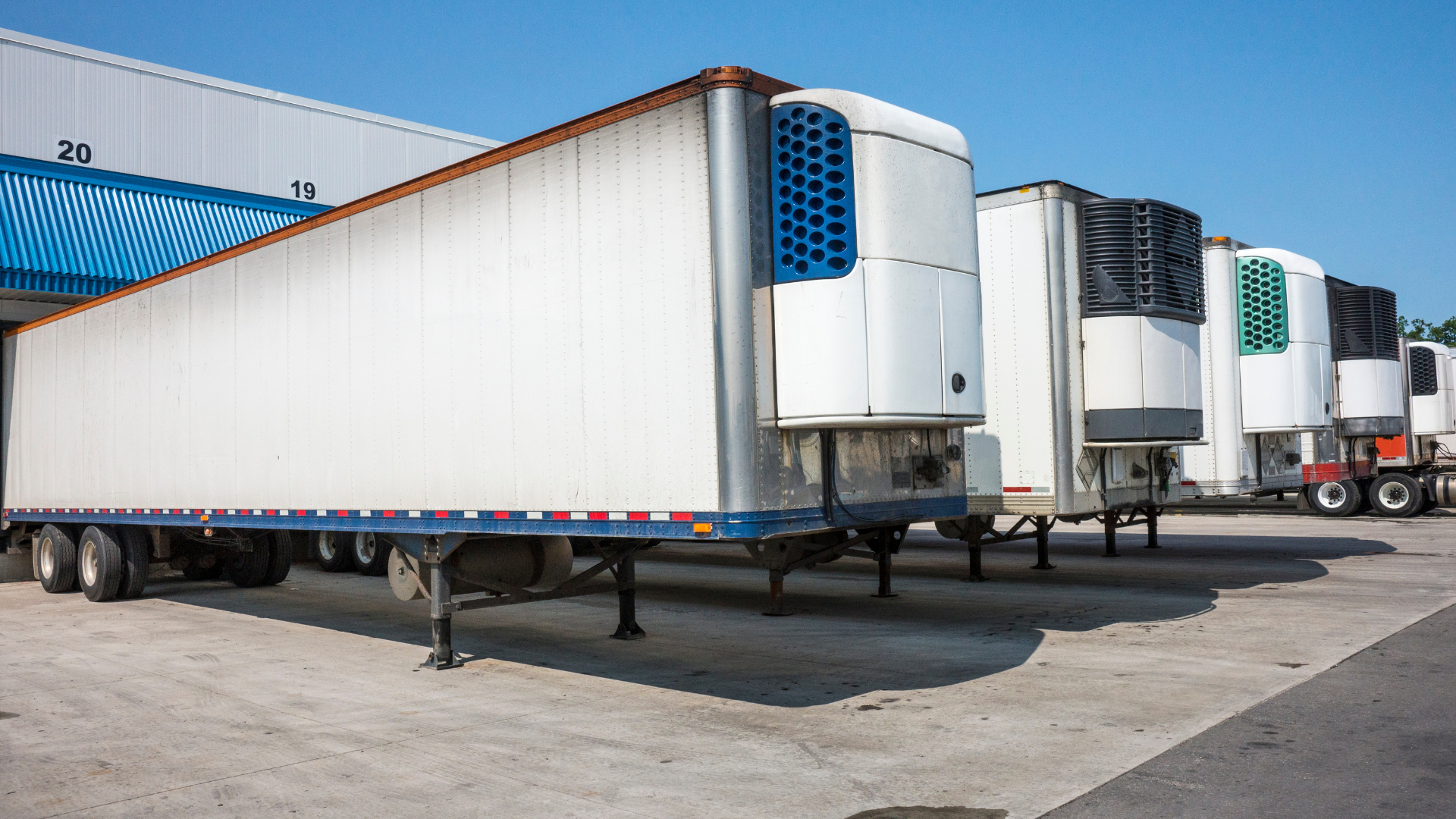 A row of semi trucks parked in front of a building.