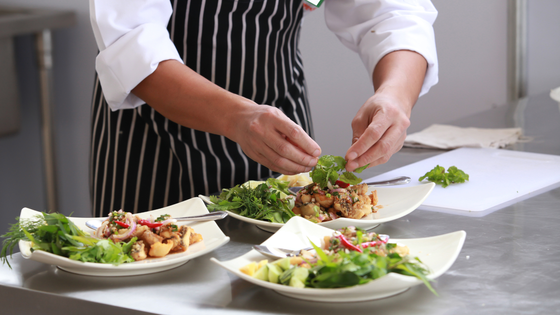 A chef is preparing plates of food in a kitchen.