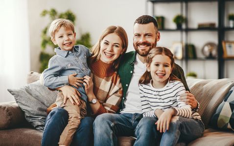 Smiling family of four sitting on a couch in a bright living room