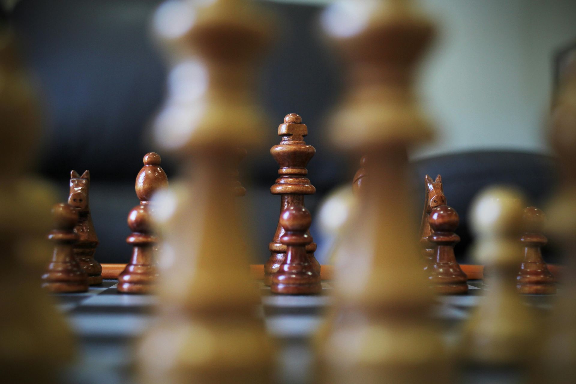 Pièces d'échecs sur un échiquier, avec une pièce centrale haute et nette, et des pièces floues en arrière-plan.