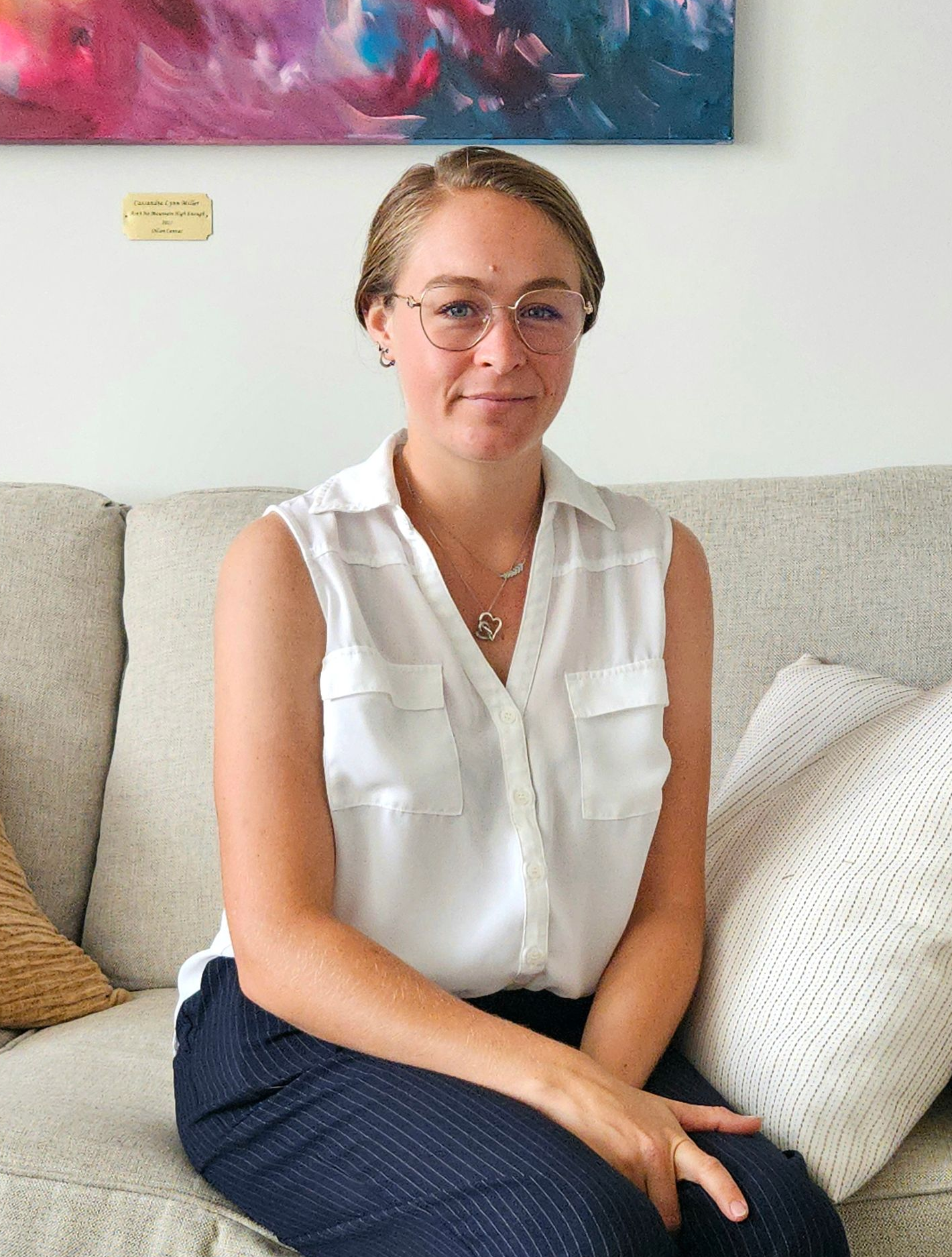 A woman with brown hair and glasses smiling and facing the camera.