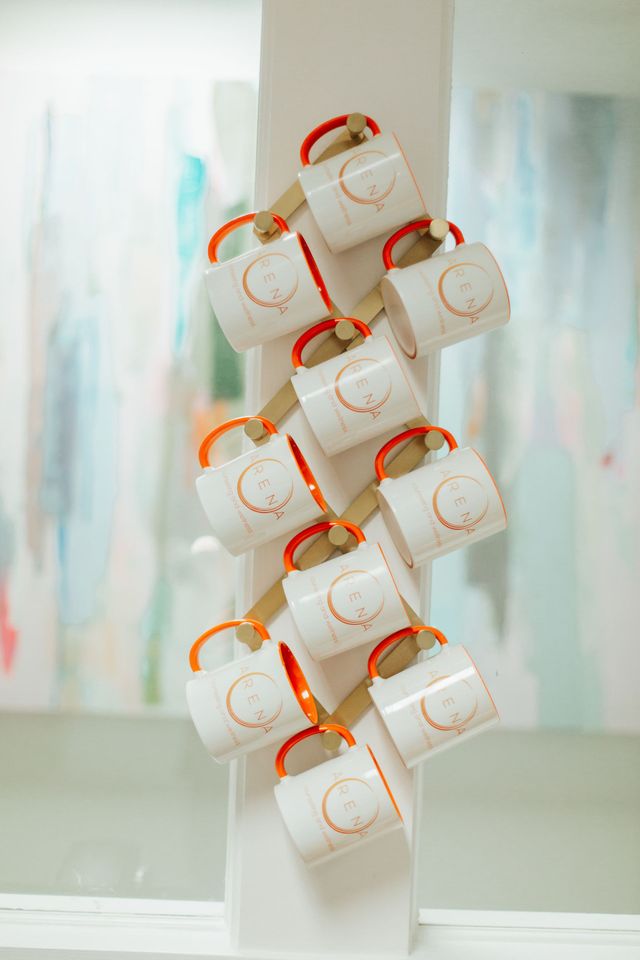 A bunch of coffee mugs hanging on a wall.