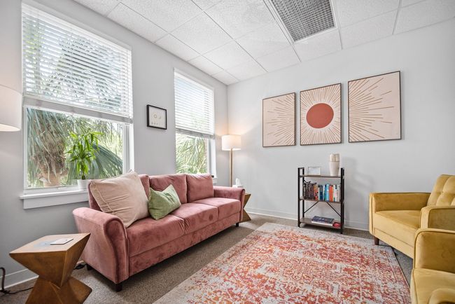 A living room with a pink couch and two yellow couches.
