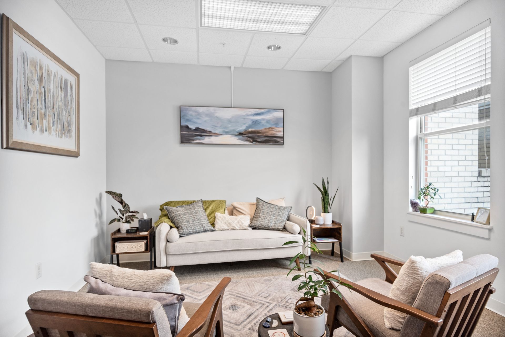 A living room with a couch , chairs , and a painting on the wall.