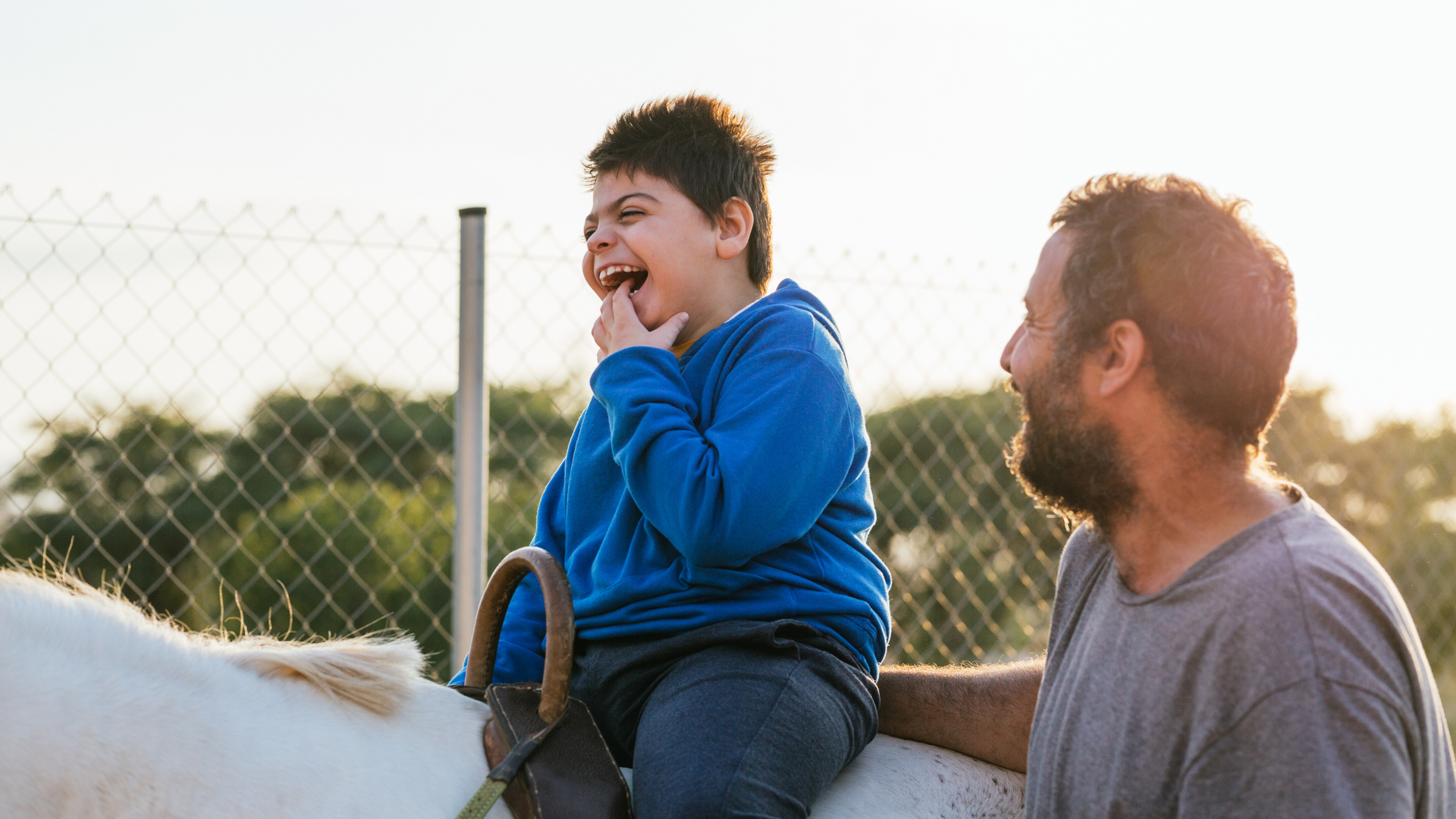 A man and a boy are riding on the back of a white horse.
