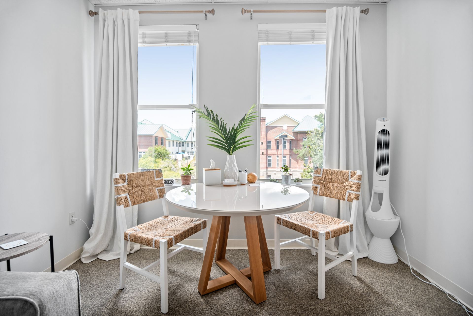 A living room with a table and chairs in front of a window.