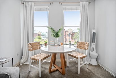 A living room with a table and chairs in front of a window.