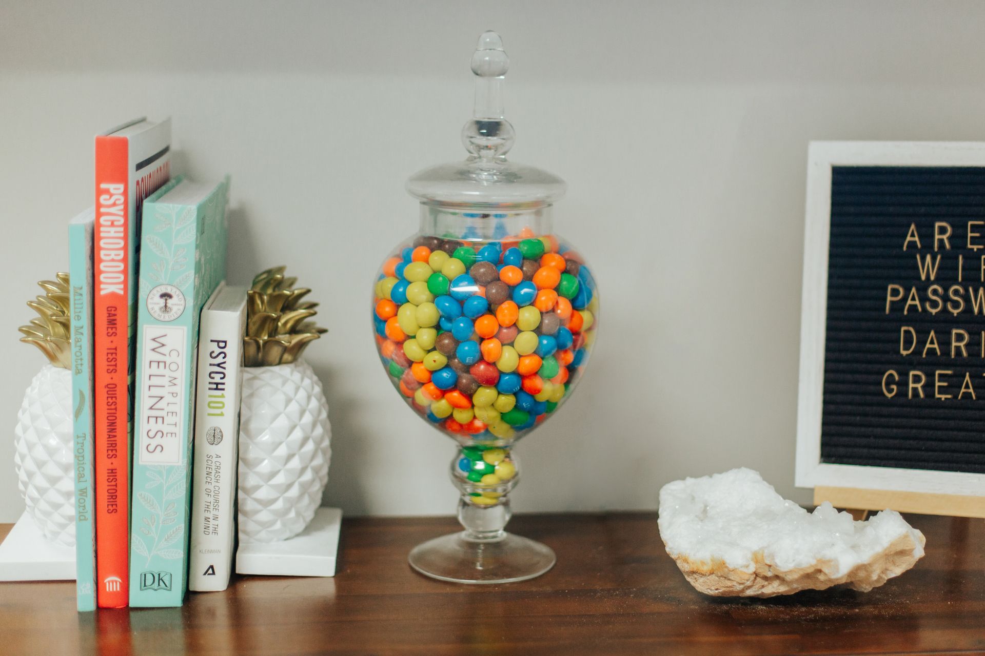 A jar filled with m & m 's is sitting on a table next to a letter board.