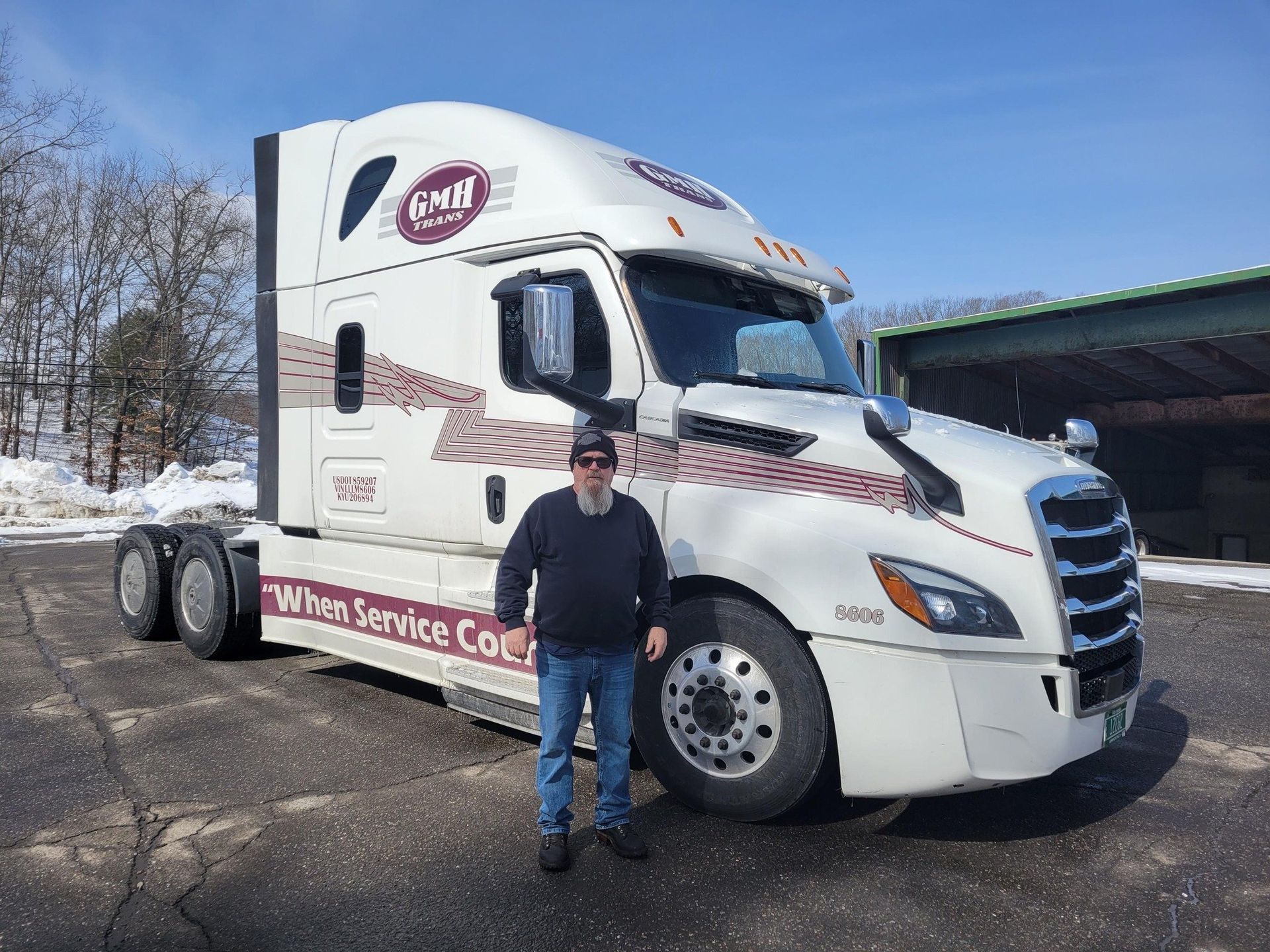 A man is standing in front of a semi truck.