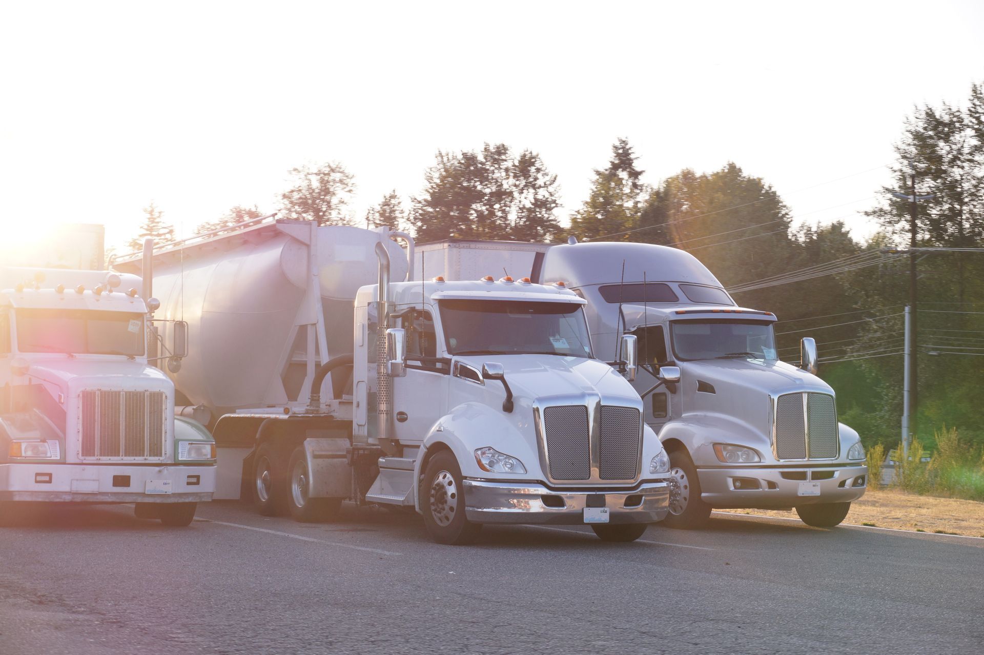Three semi trucks are parked next to each other in a parking lot