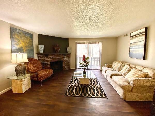 Living room with sofa, chair, fireplace, coffee table, and sliding glass door to a balcony.