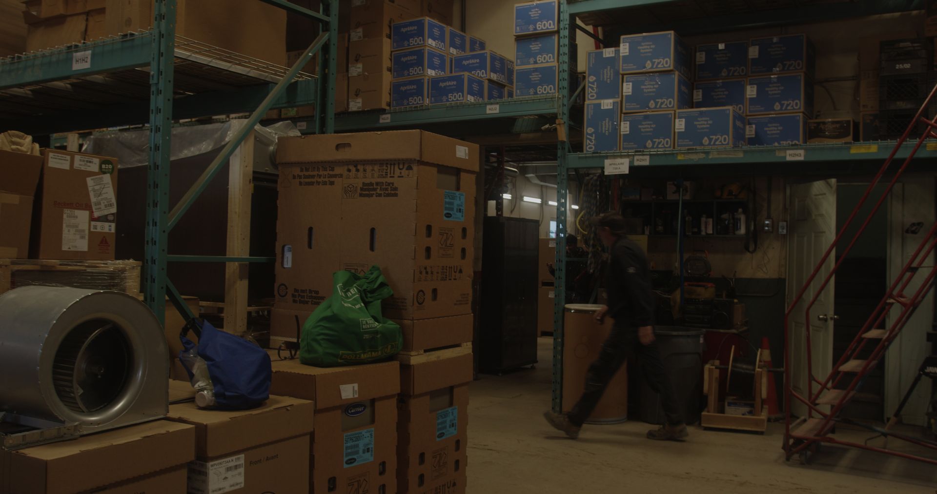 Un homme marche dans un entrepôt rempli de nombreuses boîtes.