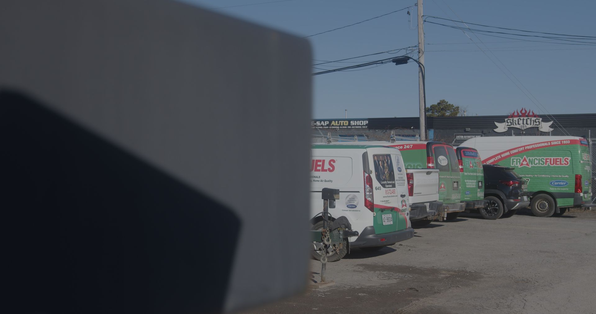 Une rangée de camionnettes vertes et blanches est garée sur un parking.
