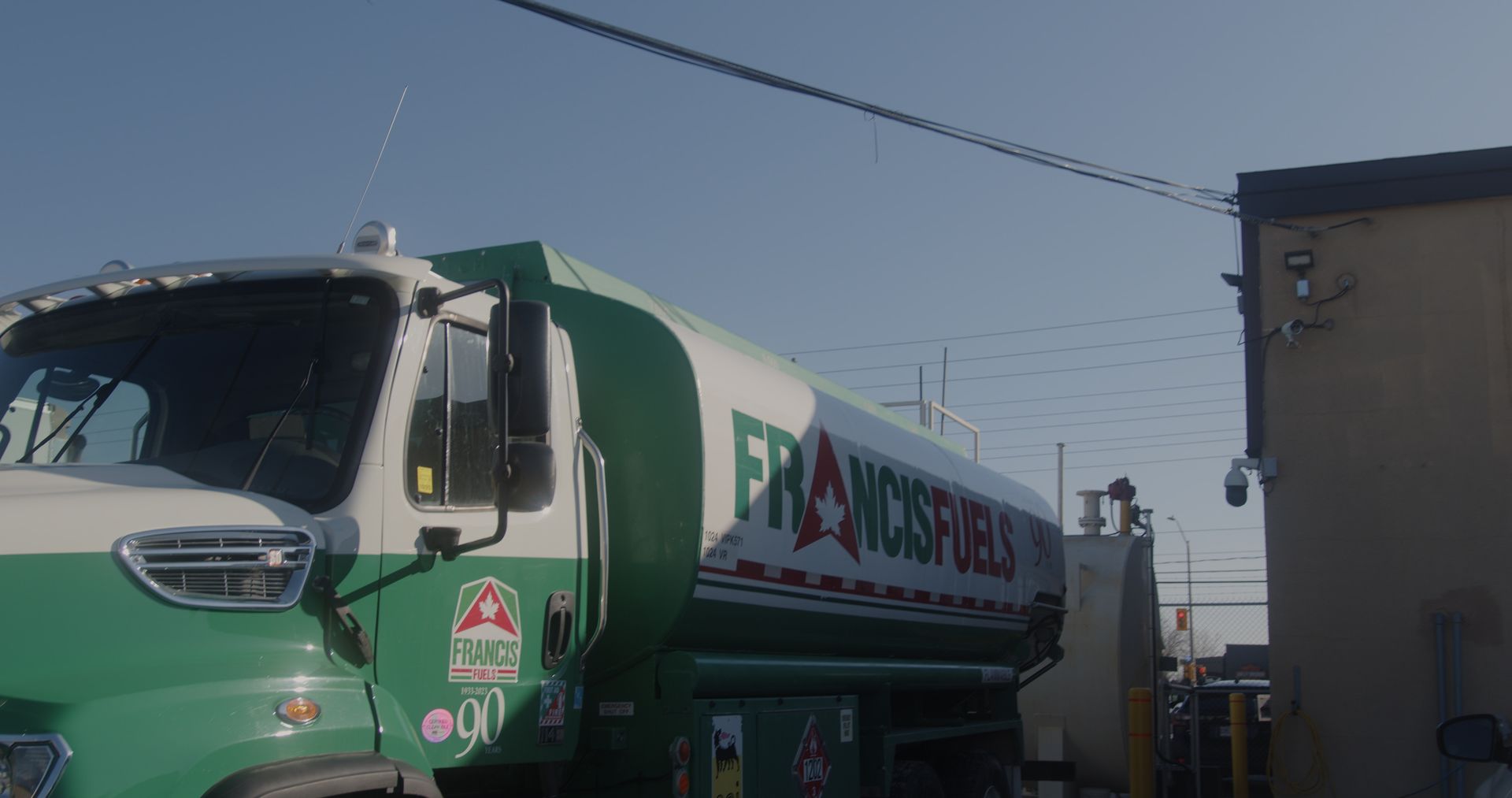 Un camion-citerne vert et blanc est garé devant un bâtiment.