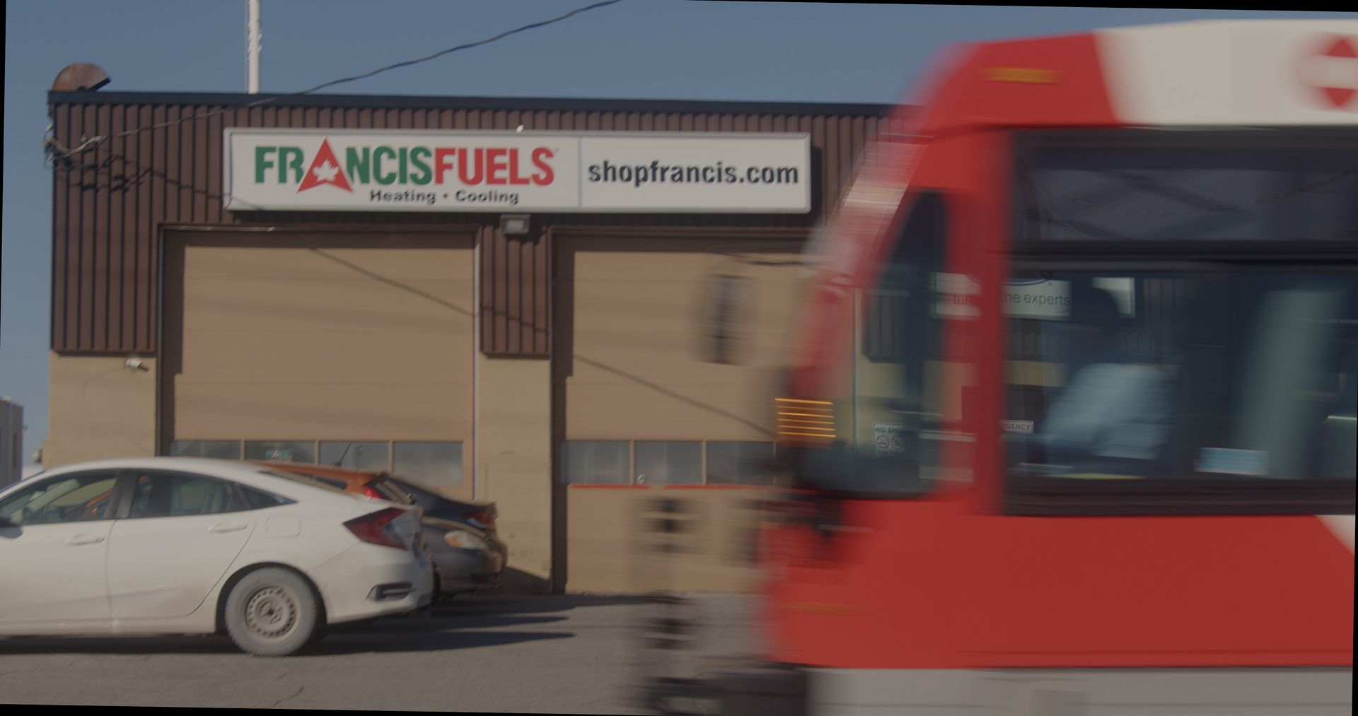 Une voiture blanche est garée devant un bâtiment sur lequel est écrit francisfuels