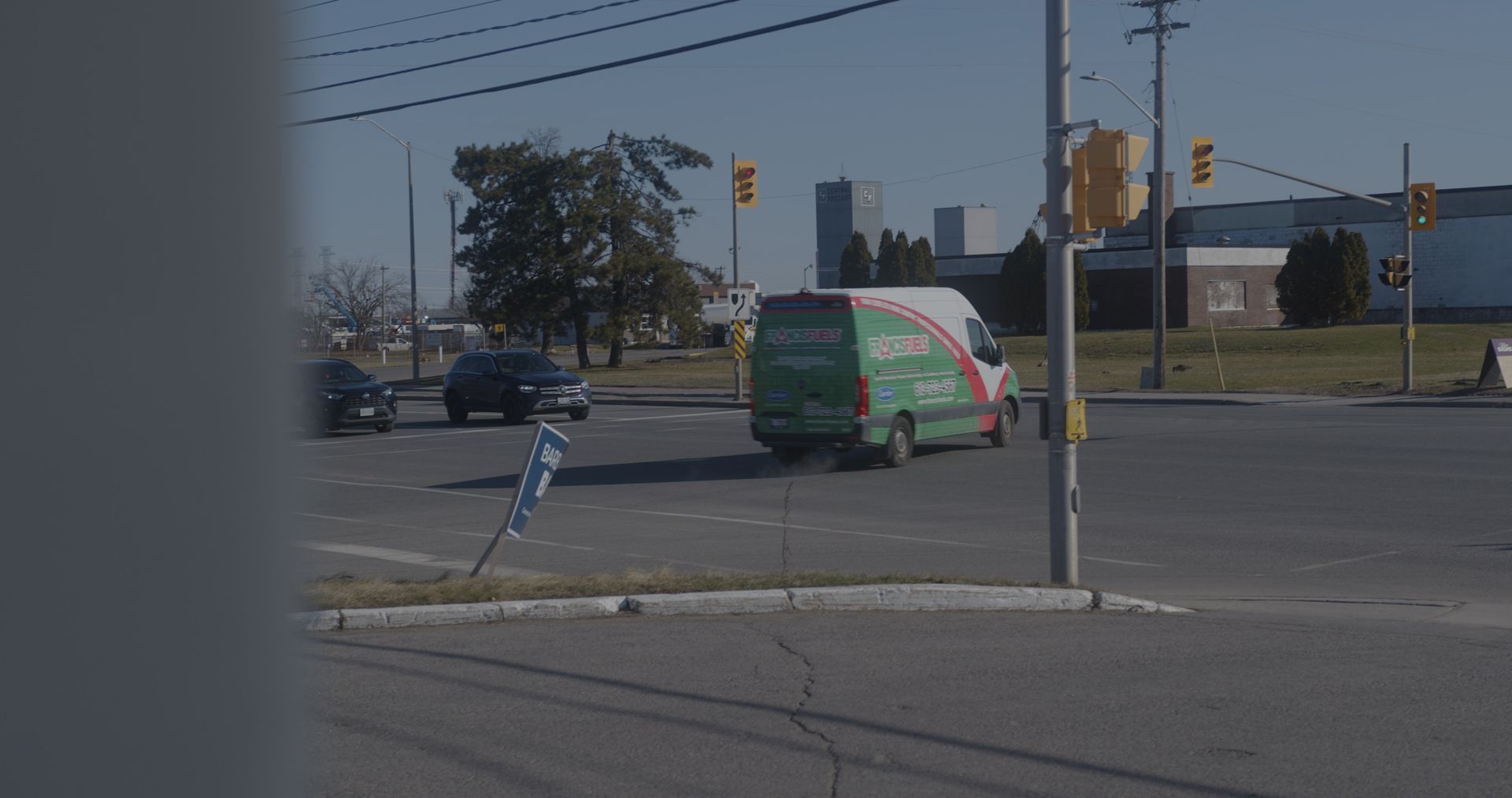 Une camionnette verte roule dans une rue à une intersection.