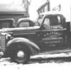 Une photo en noir et blanc d'un vieux camion garé devant un bâtiment.
