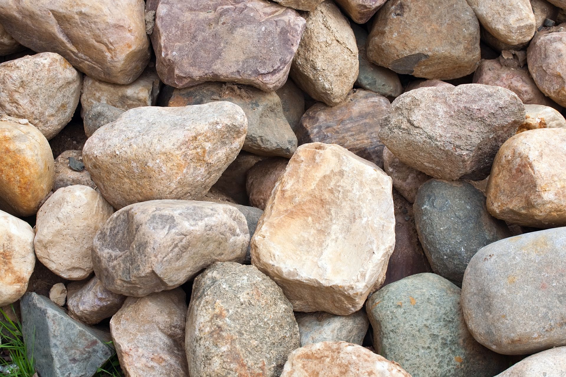 Pile of smooth, varied-colored rocks, including tan, brown, and grey, filling the frame.