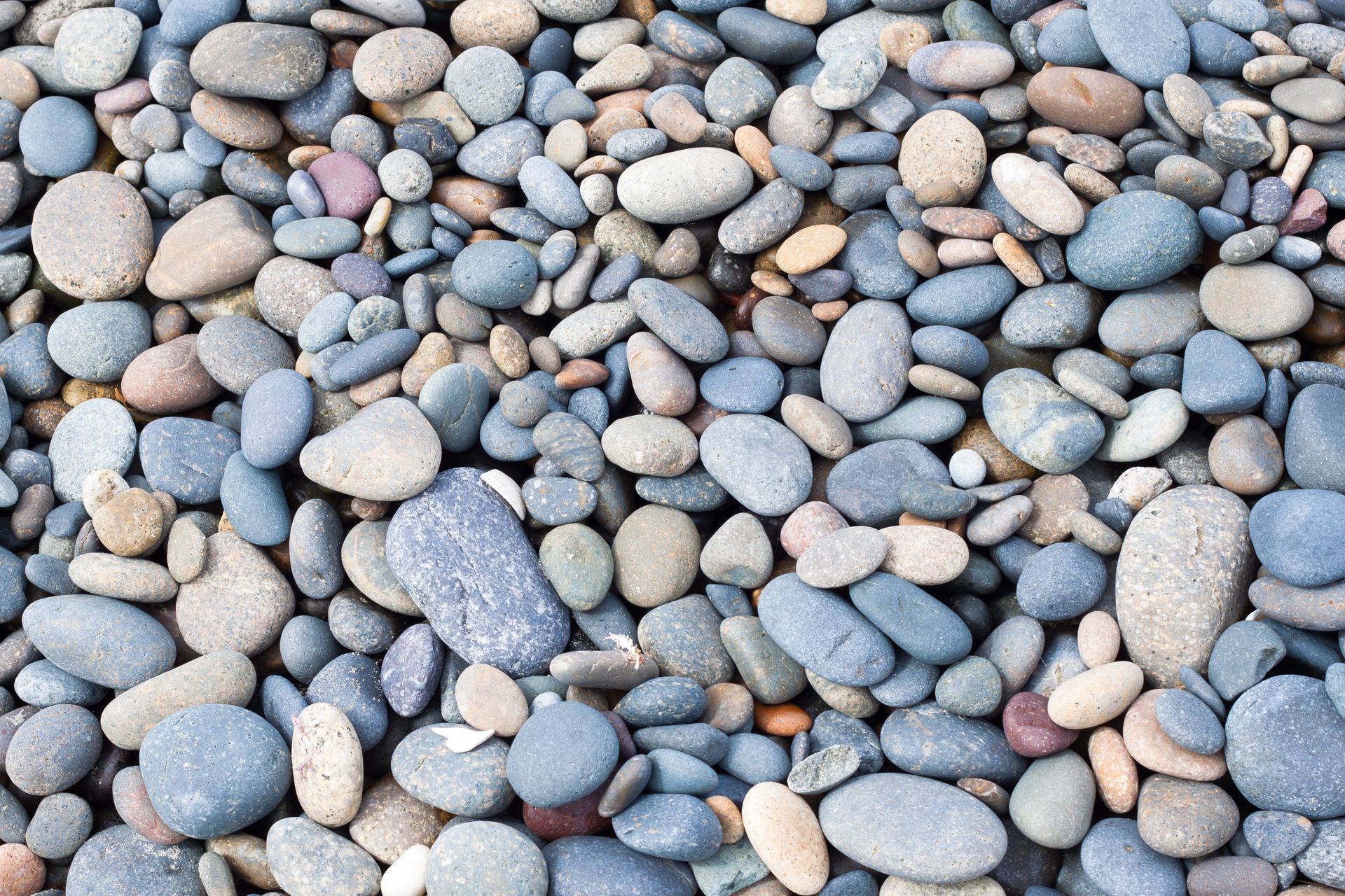 Close-up of a pile of smooth, rounded stones in shades of gray, blue, and tan.