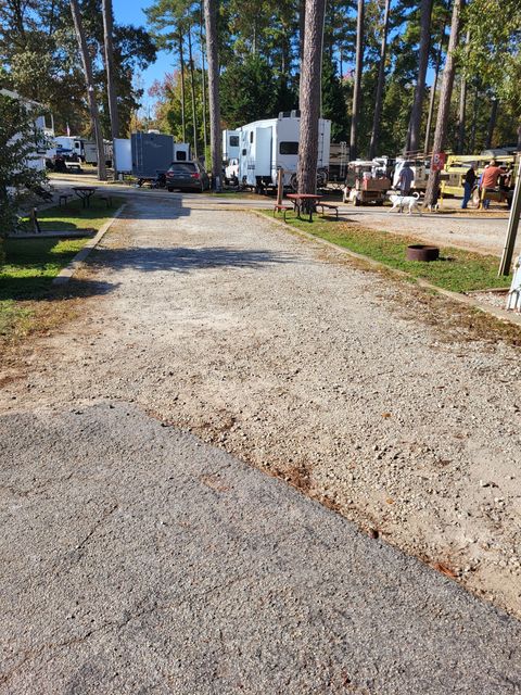 A gravel road leading to a campground with a lot of rvs parked on the side of it.