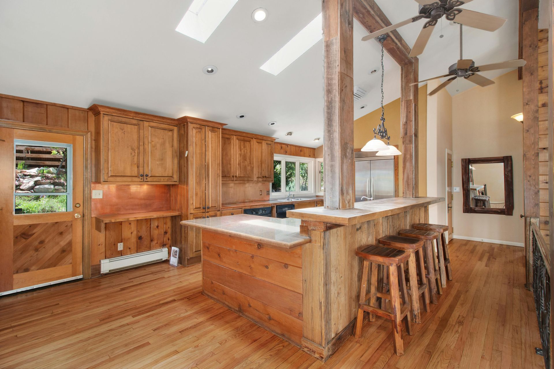 Rustic kitchen with wood cabinets, island barstools, and vaulted ceiling beams