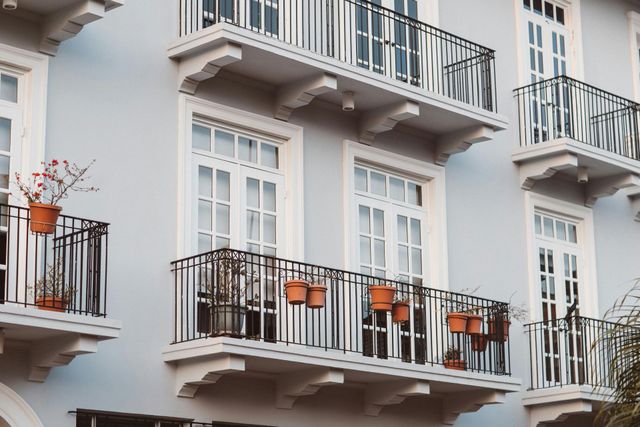 White apartment balconies with black railings and orange chairs on a building facade