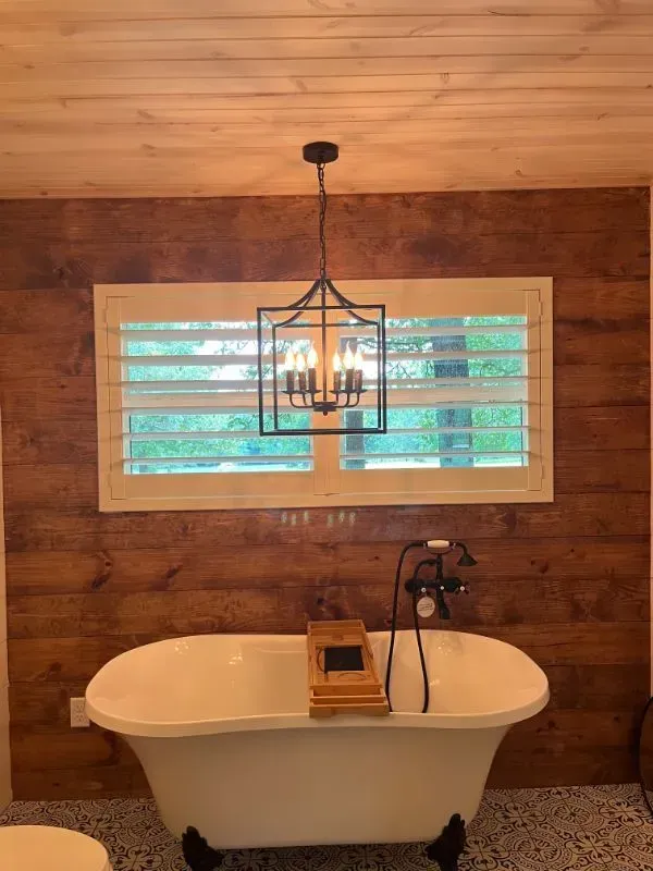 A bathroom with a bathtub and a window with shutters. Love is Blinds Arizona (844) 936-2446