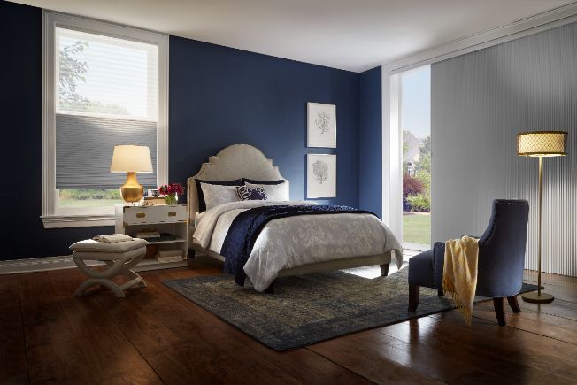A bedroom with blue walls , a bed , a chair and a lamp.