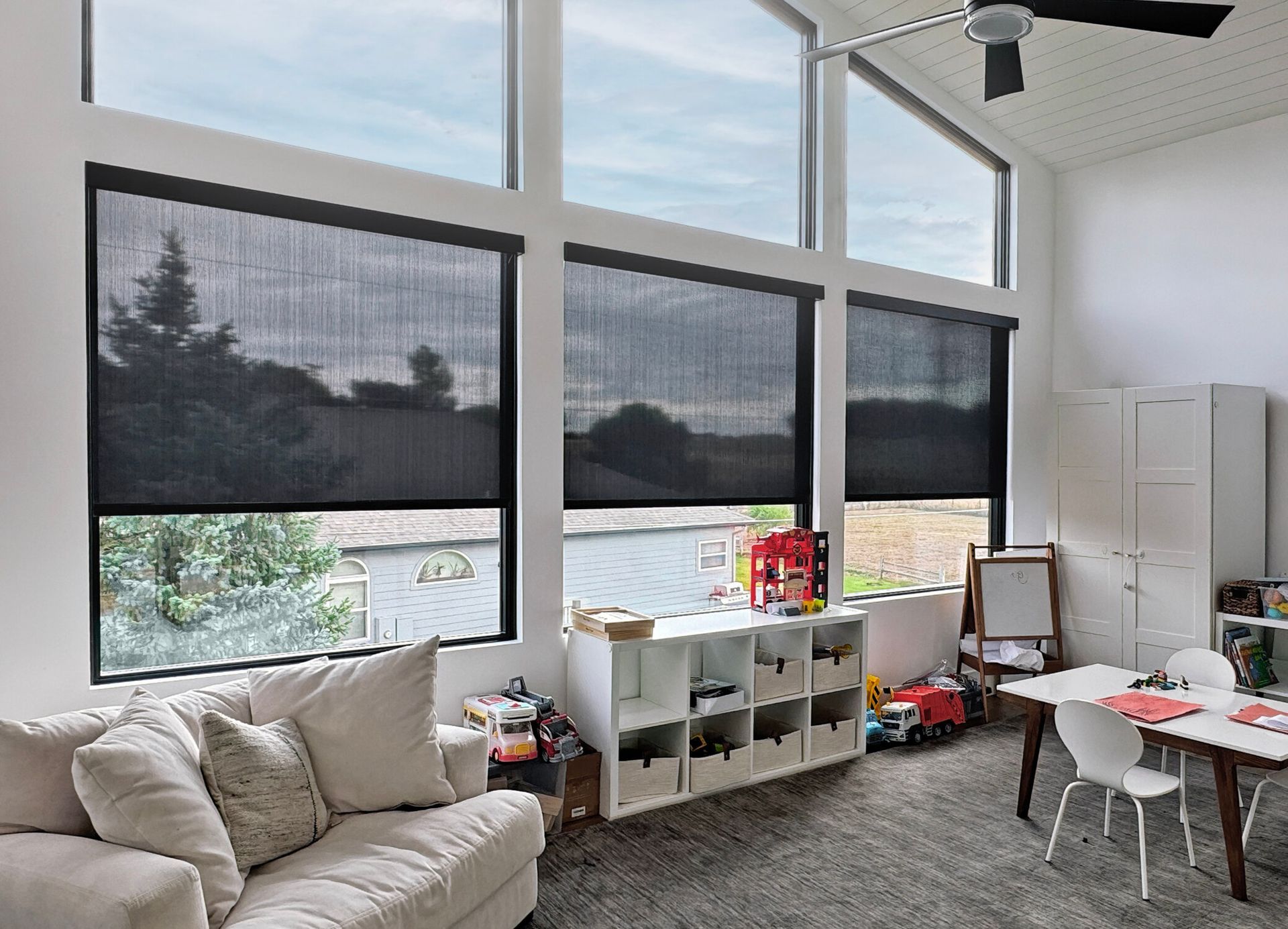A living room with a couch , table , chairs and a ceiling fan.