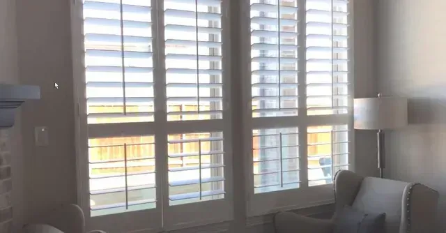 A living room with a couch , chair , lamp and shutters on the windows. Love is Blinds Arizona (844) 936-2446