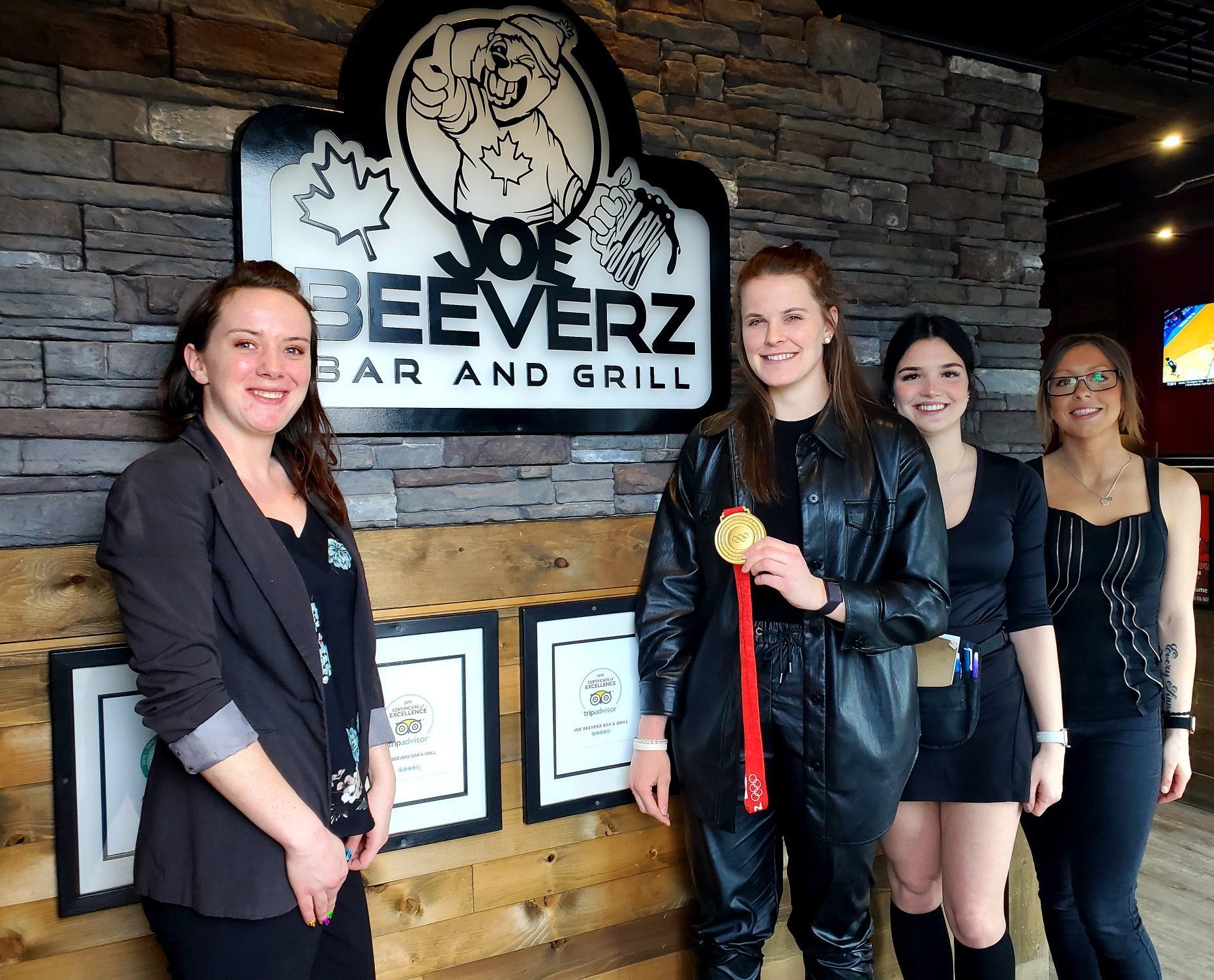 Four women posing inside a bar and grill beside the “Dog Beeverz” sign.