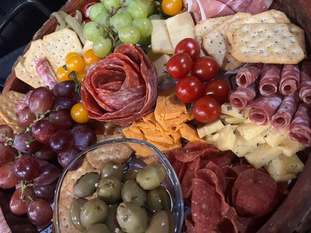 Charcuterie board with grapes, cheeses, cured meats, olives, and crackers arranged on a platter
