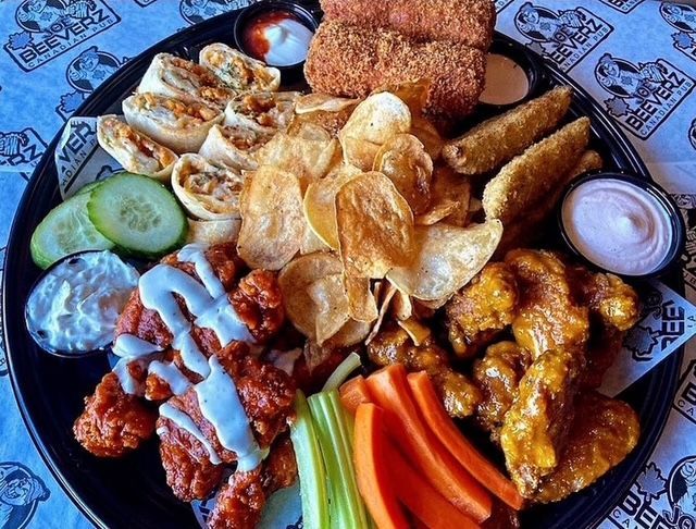 Assorted fried appetizers with dips, cucumber slices, carrots, and celery on a platter.